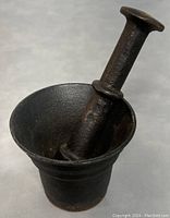 Side angle of mortar and pestle showing the cylindrical pestle resting inside the mortar with flared rim.