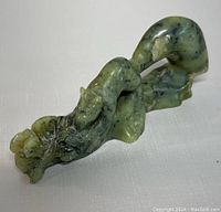 Angle view showing the squirrel on branch with detailed foliage in natural green jade with dark inclusions.
