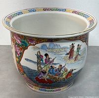 Side view of the porcelain planter showing detailed hand painted figures near water and floral patterns with geometric border.