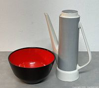 Coffee pot and Husqvarna bowl side by side, showing the coffee pot's height and design, and the glossy black and red bowl