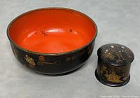 Photo showing the large lacquer bowl with red interior and black exterior with gold painted designs, next to the small black lacquer lidded trinket box