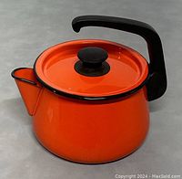 Front angle view of orange enamel teapot/kettle with black handle and lid.