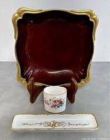 Front and three-piece view showing the square ruby red decorative Carlton Ware bowl, the floral Coalport toothpick holder, and the gold accented rectangular olive dish.