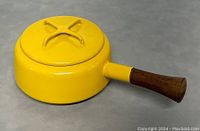 Top-down view of the yellow enamel saucepan with lid on showing bright yellow color and wooden handle.