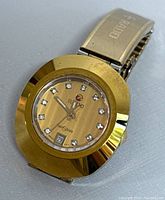 Watch face showing gold-tone dial with diamond hour markers, Rado logo, Diastar text, date window