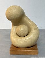 Front view of the abstract stone mother and child sculpture on wooden base