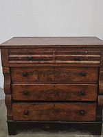 Front view of antique dresser with all drawers closed, showing wood grain and wood knobs.