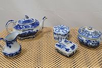 Set of five blue and white vintage porcelain china pieces on a woven mat surface.