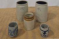 Overview of all five crocks and jars displayed on a woven mat surface showing size and color variations