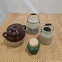 Four ceramic serving pieces on woven mat background: preserves crock, canning crock, green ginger jar, and bean pot.
