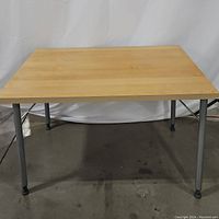Full view of rectangular laminate top folding table with metal legs, showing size and leg design.