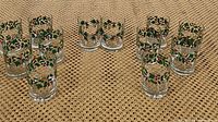 Set of 12 old fashioned glasses arranged on a woven surface, showing holly and berries decorations.