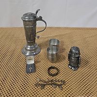 Full lot showing all metal items including robot bank, pewter stein, cups, bracelets, and necklace