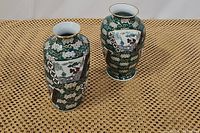 Pair of green porcelain vases shown side by side on patterned mat, displaying overall shape and design.