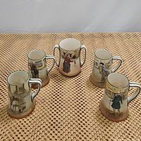Photo of the five mugs and vase, arranged on a woven surface, showing the hand-painted characters and overall style of the set.