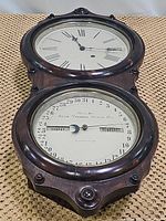 Front view of wall clock showing upper time dial with Roman numerals and lower calendar dial