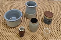 Overview of six various ceramic crocks and jars in speckled blue, cream and brown colors, showing size and style variety.