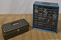 Photo showing blue metal hardware organizer and small dark green metal toolbox side by side.
