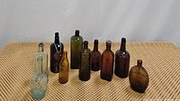 Overview photo showing the assortment of 11 vintage glass bottles arranged on a textured surface.