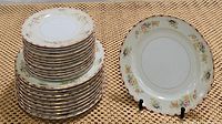 Stack of 10 dinner plates with one displayed on a stand showing pale yellow floral design with gold scroll border
