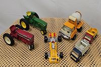 Overview of seven vintage toy vehicles including tractors, race car, and construction trucks