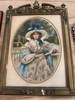 Antique framed oval portrait showing woman in vintage dress seated and holding a book. Frame has floral decorations and shows damage.