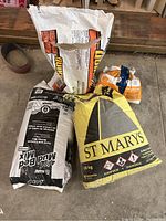 Construction material bags with St Marys Masonry Cement, Mapei Mud Bed Mix, and white mineral powder in a garage floor setting.
