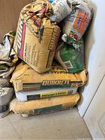Multiple bags of Quikrete concrete mix stacked on the floor, some labeled 'Mélange à béton'.