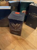 Photo showing five boxed men's colognes on wooden surface, highlighting Preferred V Conquest front and center with other brands partly visible around it.