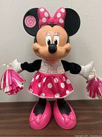 Front view of the dancing Minnie Mouse figurine in pink and white polka dot cheerleader outfit holding pom-poms.