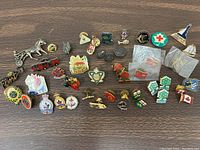 Photo showing approximately 40 assorted collectible pins including Red Cross, Canadian flags, maple leaves, and other symbols.