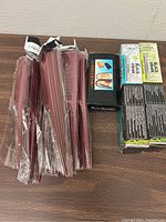 Photo showing 4 packs of Vinex Black Clean self-stick erasers and 4 packs of Vinex Eraser refills, with a box of wood supports and a box of 12 rubber erasers on a wooden surface.