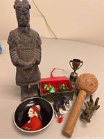 Photo showing all items in the collectible lot arranged together including the Chinese soldier figurine, Dante plate, cricket boxes, mallet, small trophy, wolf, and dragon figurines.