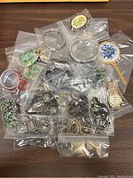 Top-down image showing assorted vintage costume jewelry items individually bagged and arranged on wood surface.