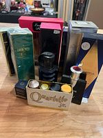 Photo showing multiple unopened boxed perfumes including Diamond Emerald by Elizabeth Taylor, Versace Dylan Blue, and a set of small perfume vial samples labeled Quartette Jr.