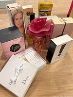 Photo showing a variety of boxed perfumes and unboxed perfume bottles including a distinctive pink rose-shaped bottle cap and Dior sample set.