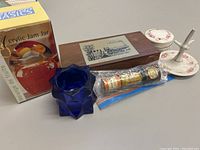 Photo showing the boxed Kitchen Basics Acrylic Jam Jar, blue glass container, wooden box with train illustration, miniature hot sauce bottles in a plastic bag, and floral patterned ceramic items.