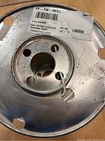 Close-up of metal spool with label showing tracer wire reel details including length and receipt info.