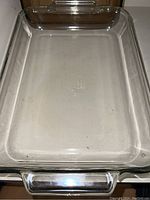 Photo showing clear rectangular Pyrex glass baking dish with handles and visible wear markings.