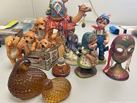 Wide angle photo showing entire lot including dog figurines, camel rider, children figurines, amber glass ducks, and decorative mask.