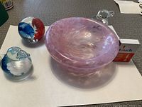 Top and angled views of the pink swirl art glass bowl with three art glass paperweights shaped as birds and sphere with colorful swirls.