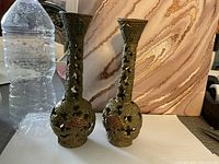 Pair of brass candle holders with textured surface and cut-out star shaped designs shown next to a water bottle for scale.