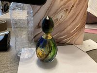 Photo of the multi-color crystal perfume bottle standing upright next to a large water bottle for size reference.