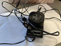 Photo of the Deluxe Universal AC Adapter showing dial switch for voltage selection and connectors.