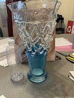 Photo showing the glass art vase beside a plastic water bottle for scale, highlighting the vase's clear patterned top and solid blue base.