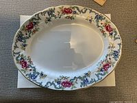 Top view of the oval porcelain serving plate showcasing floral patterned border with red roses and other colorful flowers.