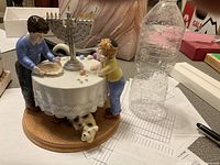 Hanukkah figurine music box showing two children at a table with menorah and dog underneath