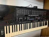 Yamaha PSR-410 keyboard showing full keyboard with keys, buttons, pitch bend wheel, and power adapter cable.