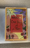 Front view of the 'Success' themed box with colorful artwork and gold-framed title.