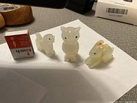 Three small hand carved onyx animal figurines including a cat, squirrel, and rabbit placed beside a matchbox for scale.